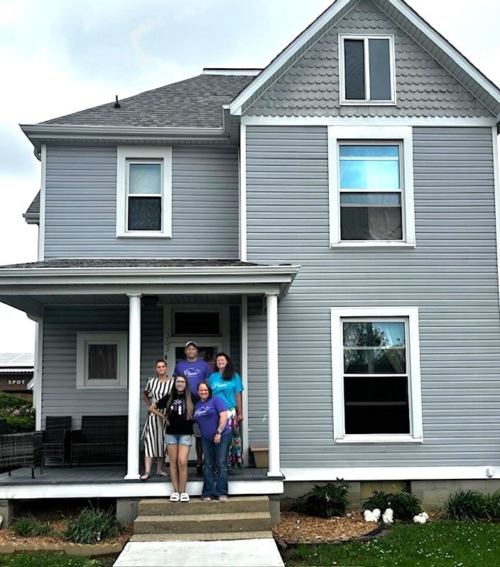 five persons, some Certified Recovery Support Specialists and others additional interns staffing Haven Home, stand on the two story gray house front porch 